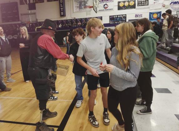 Top: Veterans Tom Howard, Jimmie Porter, and Jerry Collins (L-R) prepare to share some educational videos with the Rye High School students. Left: Jimmie Porter, Quartermaster at VFW Post 7305 passes out traditional Veterans Day red poppies Below: Veteran Don Shumake shakes hands with Rye High School students after sharing his experiences in the US Marines. Photos by Shirley Pigg