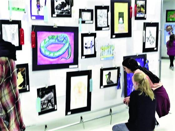 Visitors at the 2023 Student Art Show and Concert examine some of the art displayed at Rye High School for the March 8 event. Photo by Shirley Pigg
