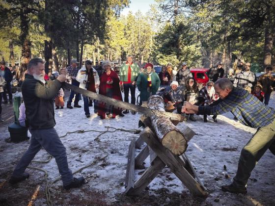 Head huntsman David Martin (L) and 2024 Yule log finder Tom Green cut the Yule log. Courtesy Photo
