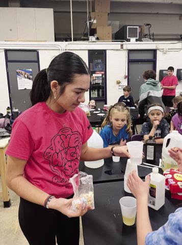 Ming Tam filling cups with different liquids to help with an experiment Courtesy Photo