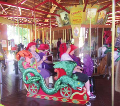 The Red Hat Ladies expience the Carousel built in 1911 by Charles Wallace Parker Amusement Devices Company. Photo by Shirley Pigg