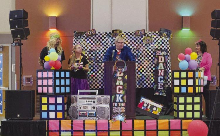 Carma Loontjer, Pueblo West Chamber of Commerce President (far right), presents the 2024 Business of the Year plaque to Sales Manager Troy English, Community Relations Manager Emily Briggs, and Highline Internet CEO Rob Mills (L to R) at a 1980’s themed ceremony. Courtesy Photo