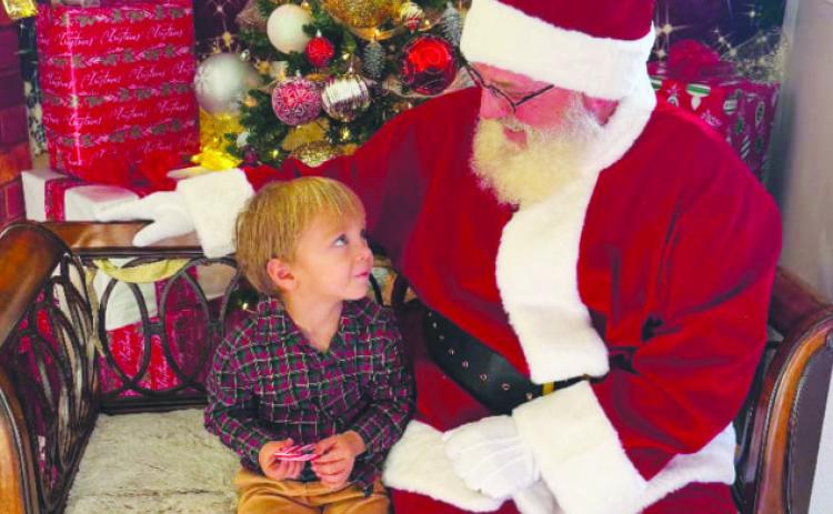 Jolly Santa listened closely as one youngster shared his wish list. Courtesy Photo