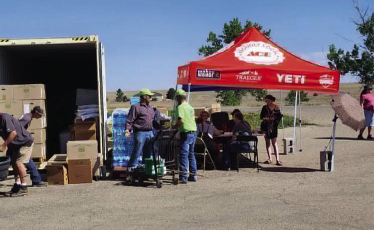 Rye Church of Christ volunteers will be stocking and handing out supplies just as they did while they were at the Greenhorn Valley Ace Hardware parking lot. Bill Mansfield (l) unloads water, an unknown person sorts through boxes, and Darrel Proctor and Jim Ragan discuss the operation while other volunteers assist customers at the tables under the tent. Photo by Shirley Pigg