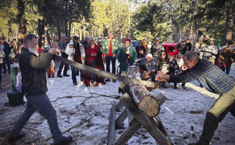 Head huntsman David Martin (L) and 2024 Yule log finder Tom Green cut the Yule log. Courtesy Photo